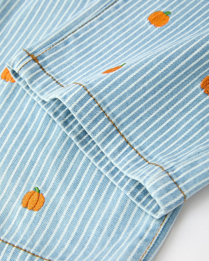 Close-up of a blue striped fabric with embroidered orange pumpkins on a white background
