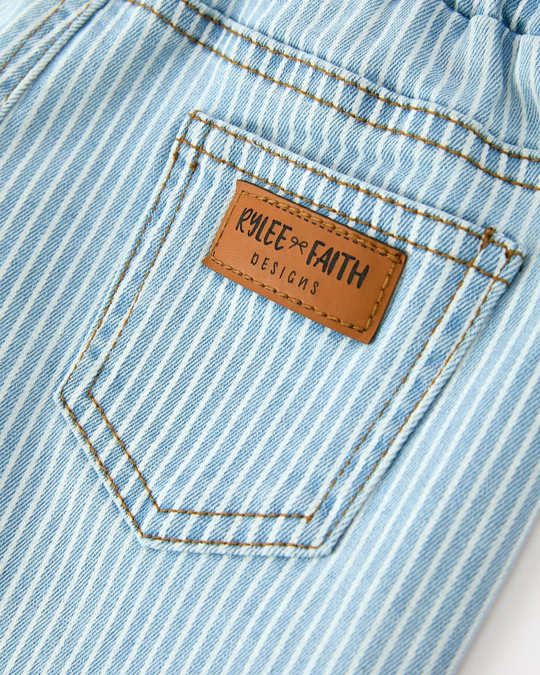 Close-up of a blue striped denim pocket with a brand label on a white background