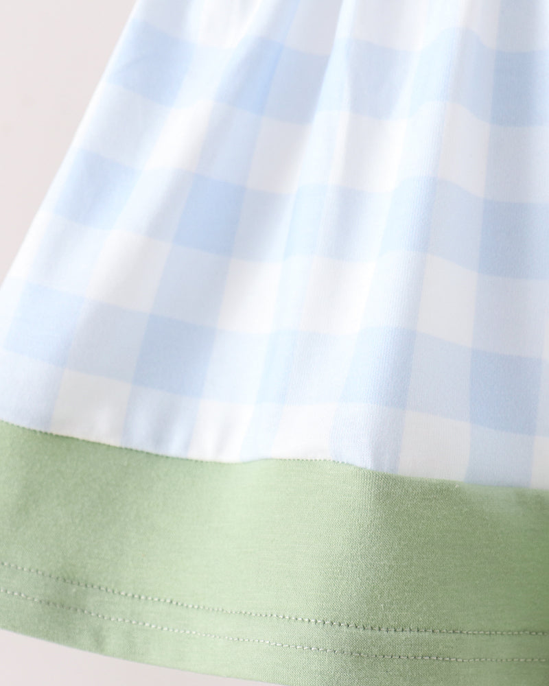 Close-up of a light blue and white gingham fabric with a light green solid band along the bottom hem.