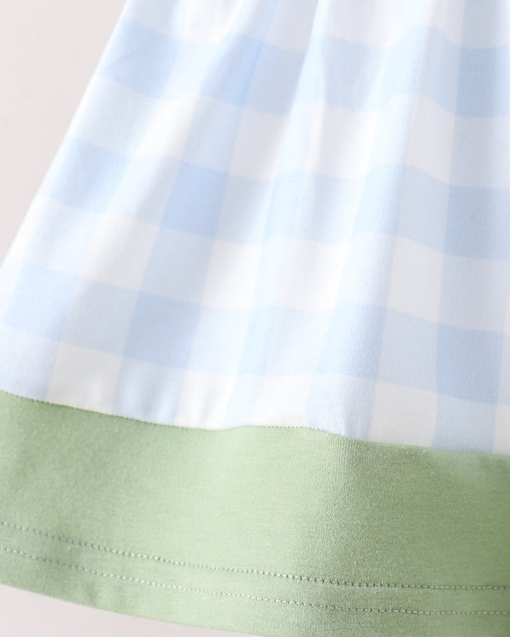 Close-up of a light blue and white gingham fabric with a light green solid band along the bottom hem.