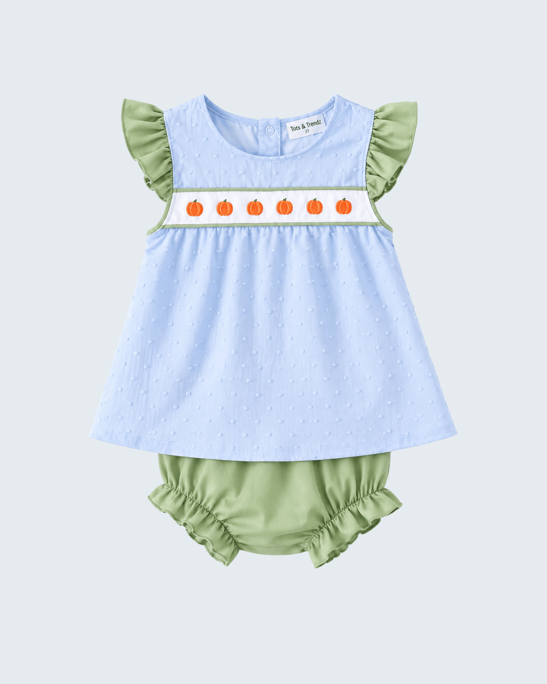 Baby girl's two-piece outfit featuring a light blue textured smocked dress with green ruffle sleeves and a white chest band decorated with orange pumpkins, paired with sage green ruffle bloomers, shown on a light gray background.