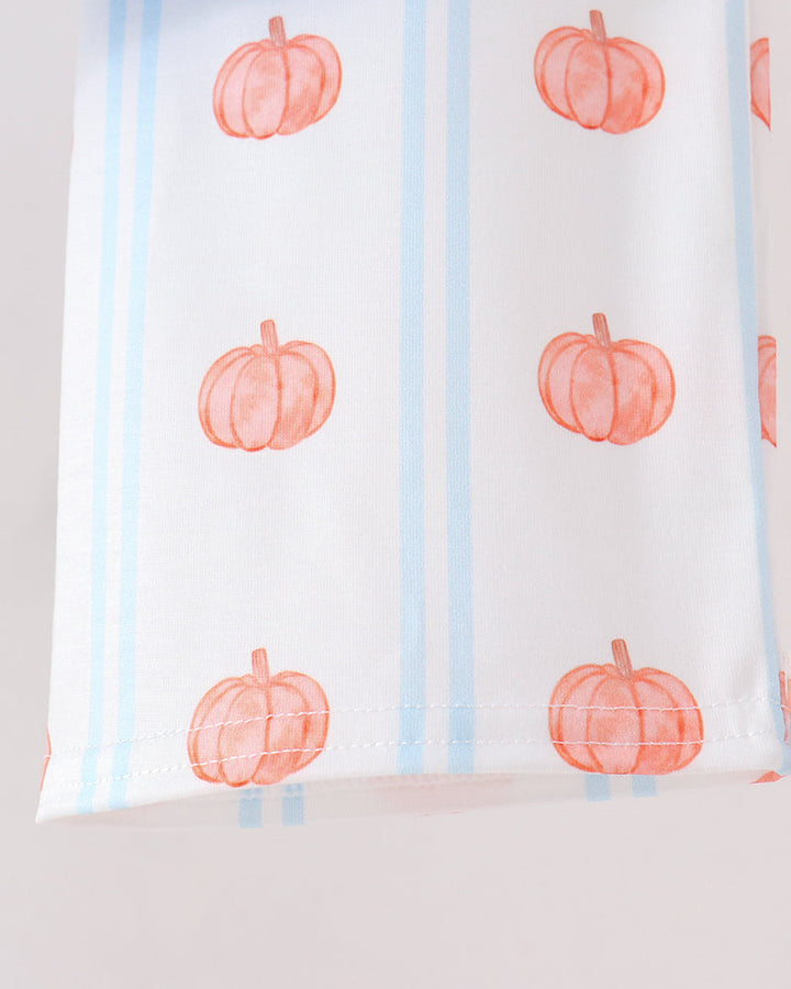 A close-up of a white fabric item, featuring a pattern of orange watercolor pumpkins and light blue vertical stripes.