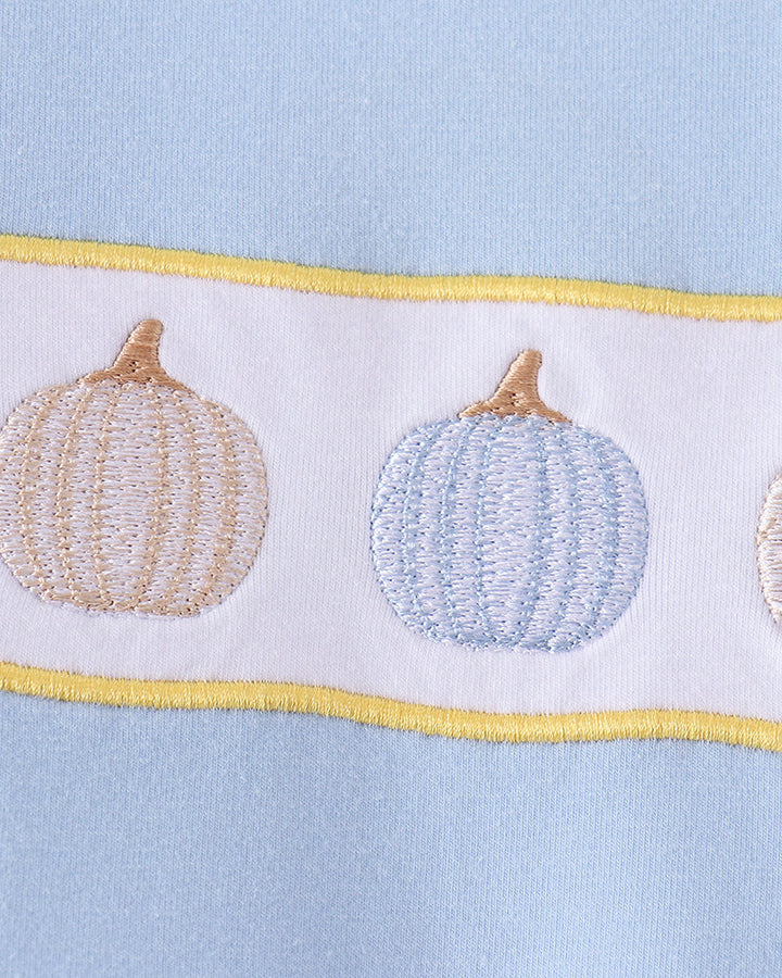 Close-up of pumpkin embroidery on light blue romper with yellow trim