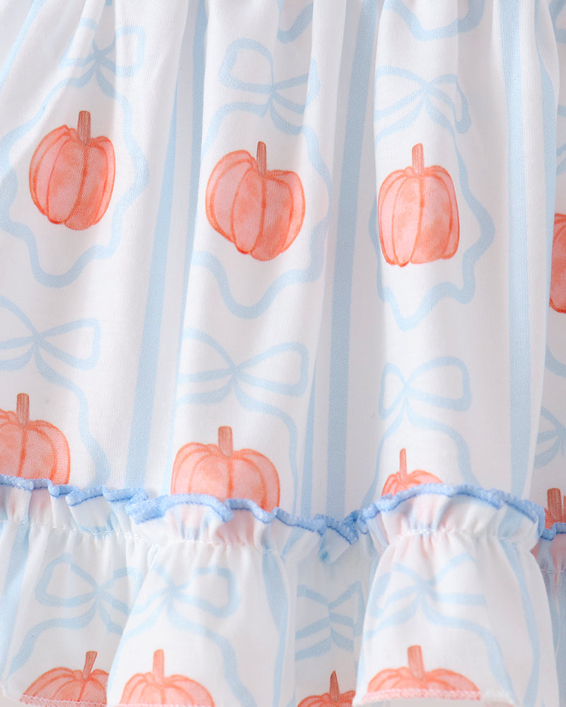 White ruffled dress with a repeating pattern of orange watercolor pumpkins and light blue bow outlines, finished with a ruffled hem.