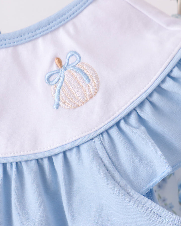 White bib panel with pumpkin embroidery and light blue ruffle neckline on the dress