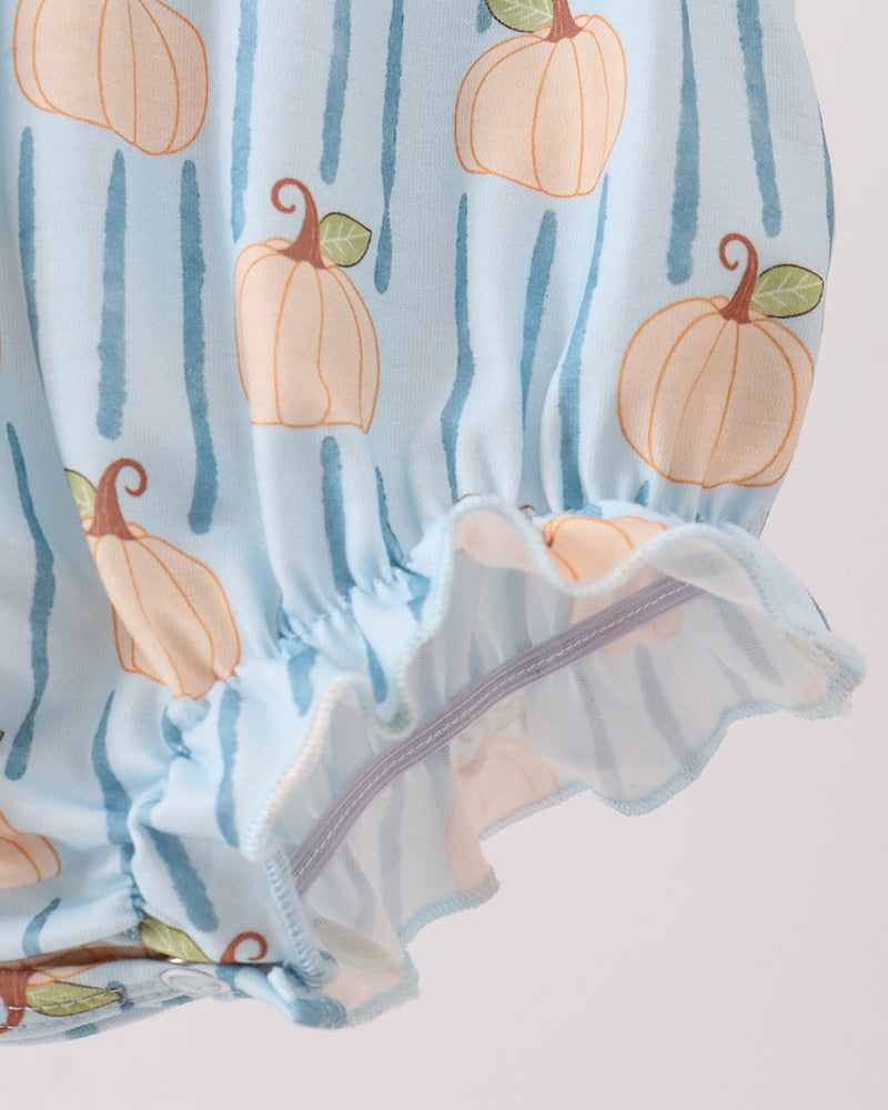 A close-up of a light blue fabric garment with a vertical stripe pattern and an all-over pumpkin print, featuring a ruffled elastic hem.