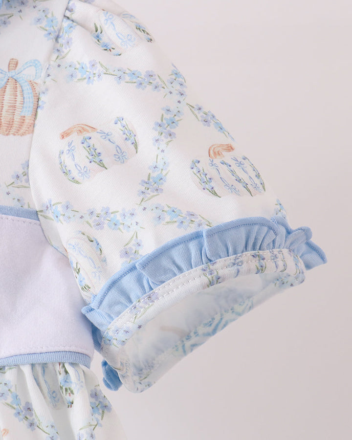 Close-up of light blue ruffle cuff on patterned dress with embroidered pumpkin motifs.