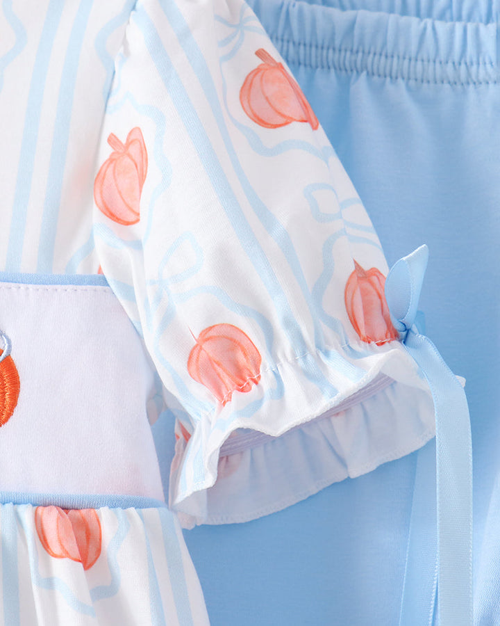 A close-up of a light blue and white striped costume dress with peach and bow patterns, featuring ruffled sleeves and a matching light blue waistband.