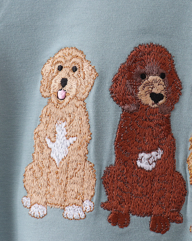 Two embroidered dog patches on a light blue fabric background.