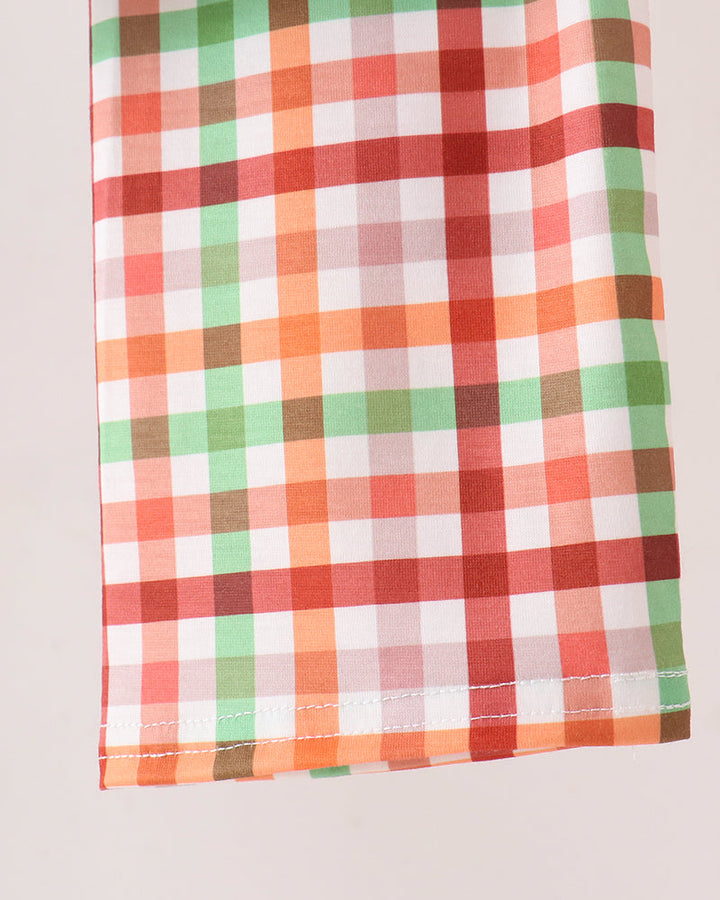 A close-up of a folded fabric featuring a multicolor gingham plaid pattern with orange, green, red, pink, and white checks on a light background.