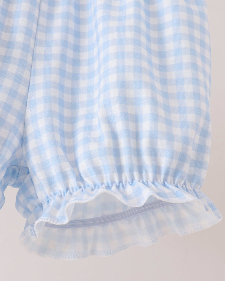 Close-up of a light blue and white gingham check fabric with a ruffled elastic hem, shown against a plain light background.
