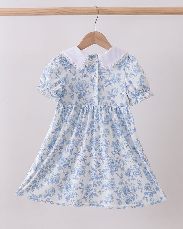 Blue Rose Smocked Dress on wooden hanger. Light grey background