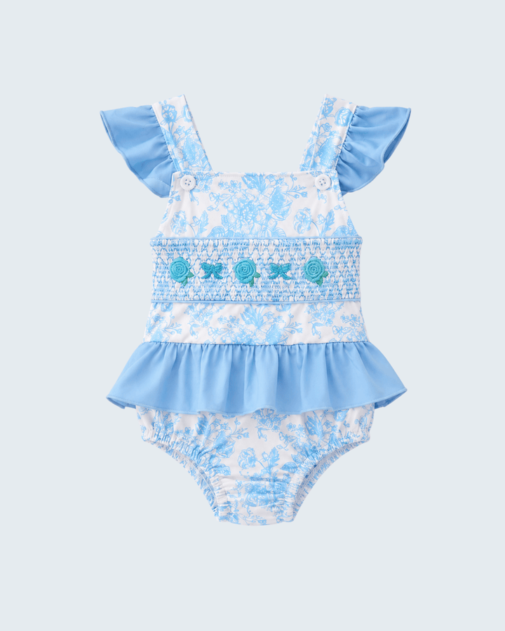 Floral baby romper with ruffled details on a light blue background