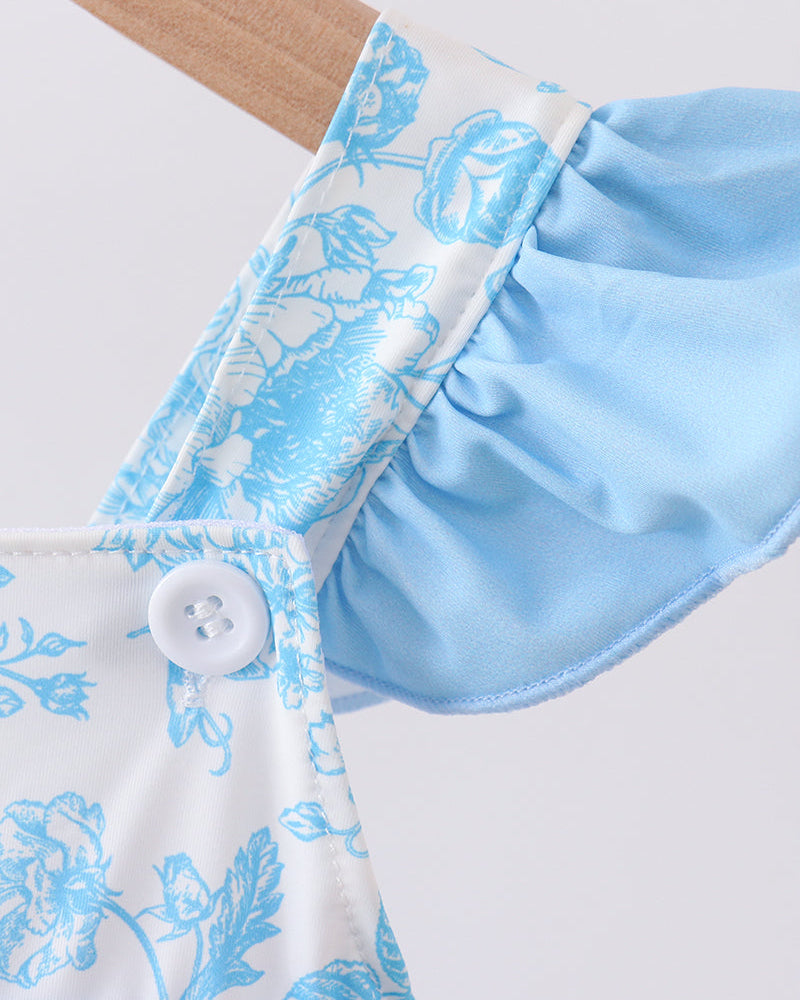 Close-up of a light blue floral-patterned swim top with a white button on a white background