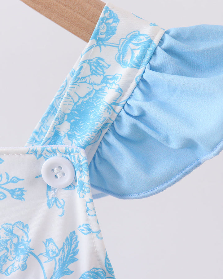 Close-up of a light blue floral-patterned swim top with a white button on a white background