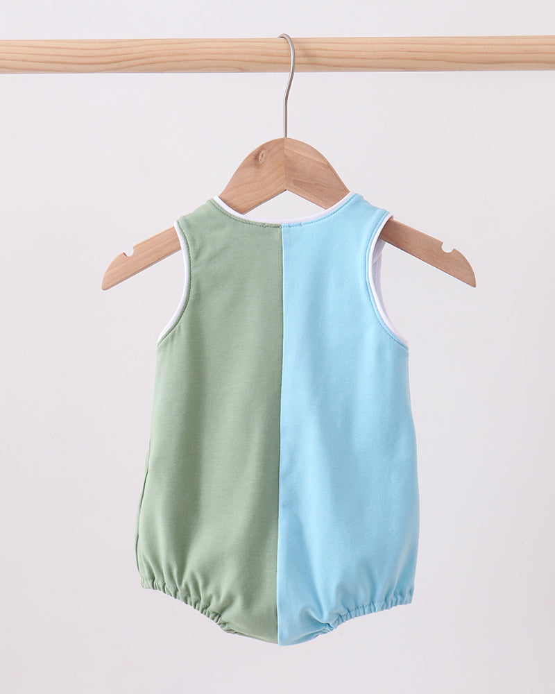 Two-tone green and blue sleeveless romper hanging on a wooden hanger against a white background.