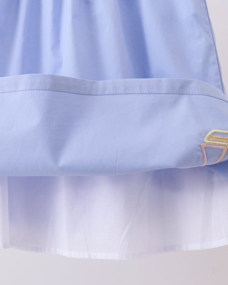 Light blue dress close-up showing gathered skirt hem and sailboat embroidery