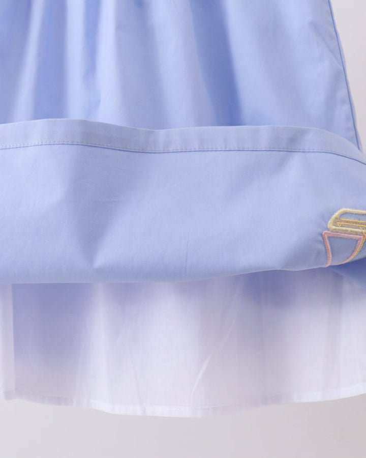 Light blue dress close-up showing gathered skirt hem and sailboat embroidery