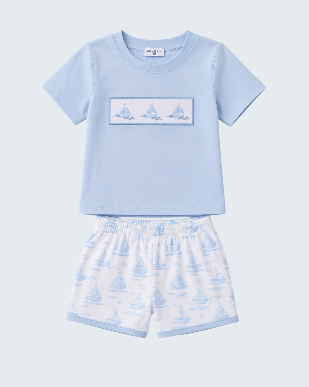 Children's blue t-shirt and shorts set with sailboat pattern on a light gray background
