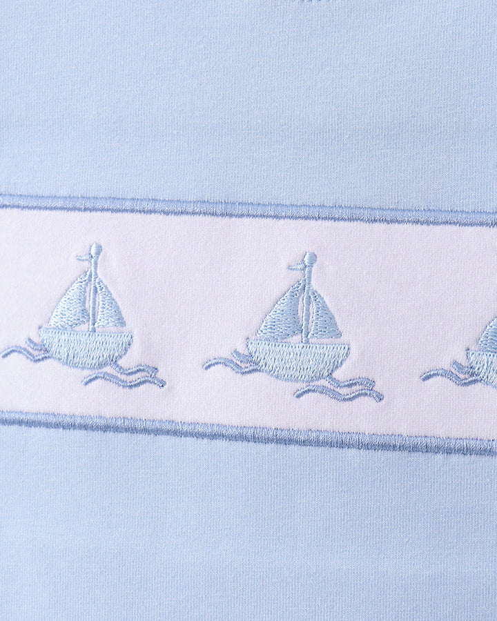 Light blue fabric with embroidered sailboat designs on a white background
