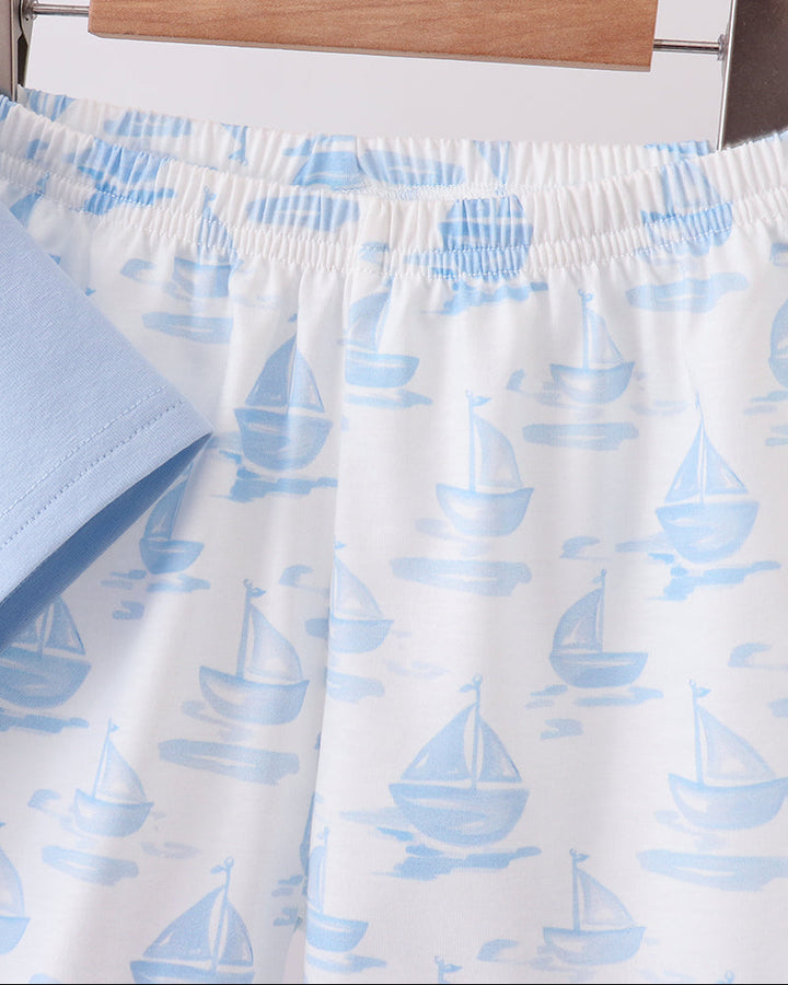 Shorts with blue sailboat pattern on a hanger against a white background