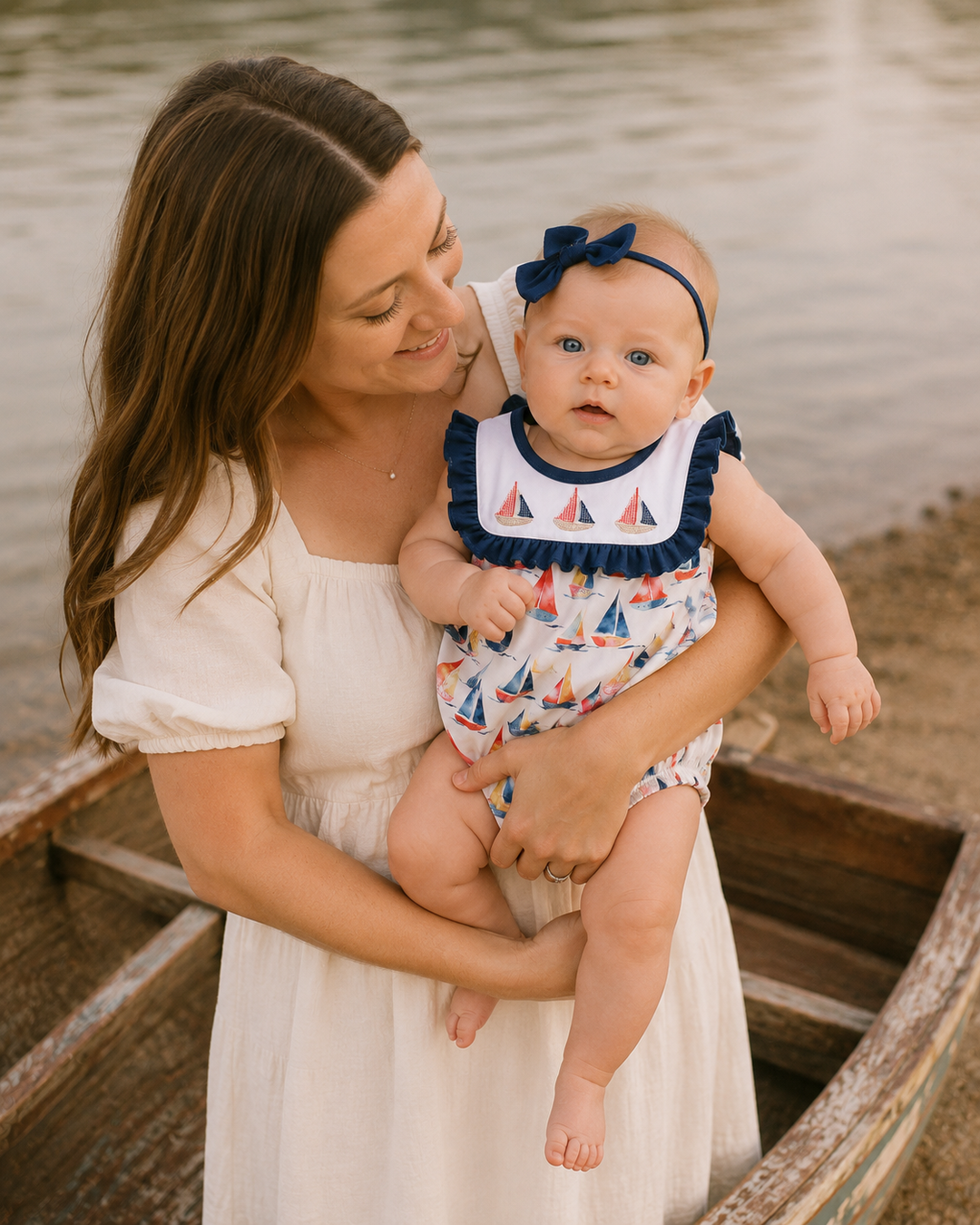Women is holding a baby girl. She is sanding is a wooden boat