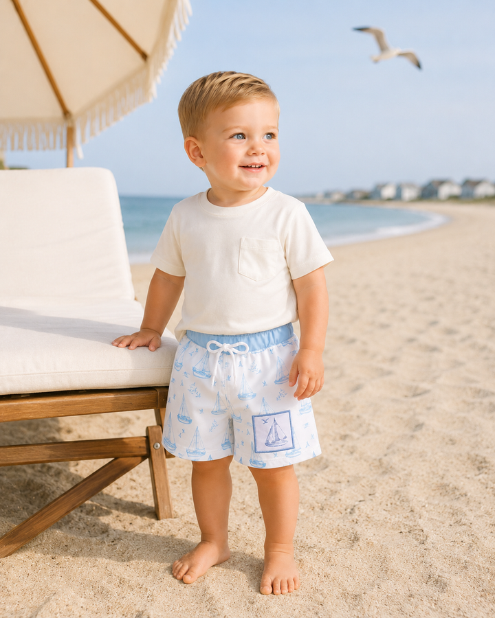 Boys swim trunks with blue sailboat print, elastic waistband and white drawstring