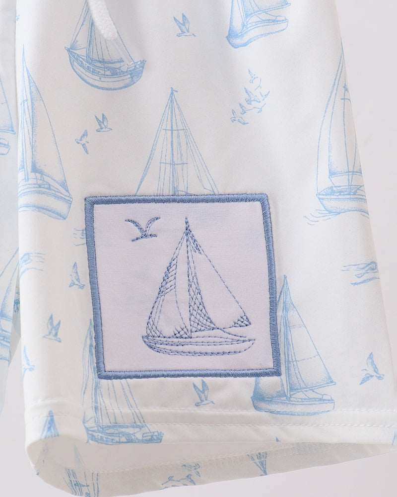 Sailboat embroidered swim trunks with blue sail patch on white fabric