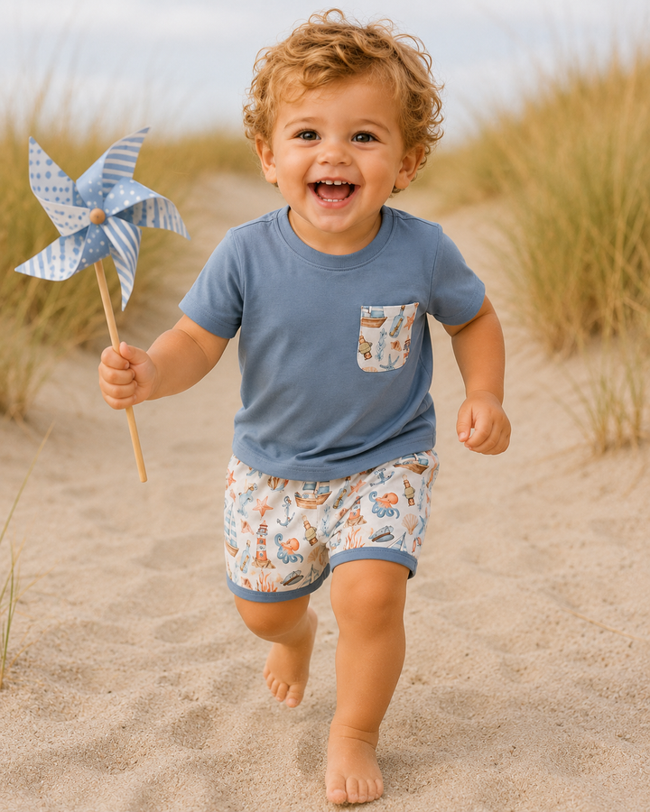Toddler running in the sand dunes. He is holding a pin wheel. 