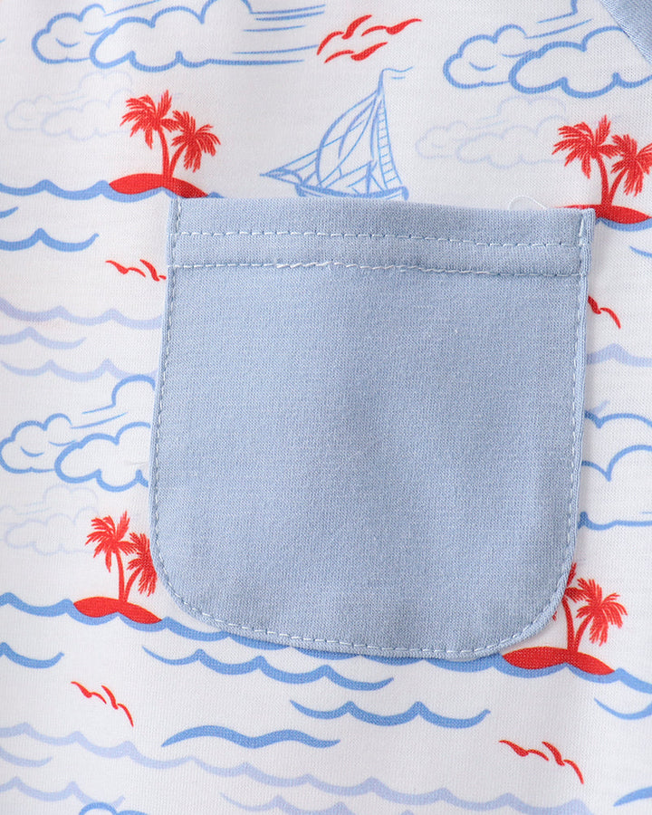 Close-up of a pocket on a shirt with a beach-themed pattern including palm trees, a sailboat, and waves.