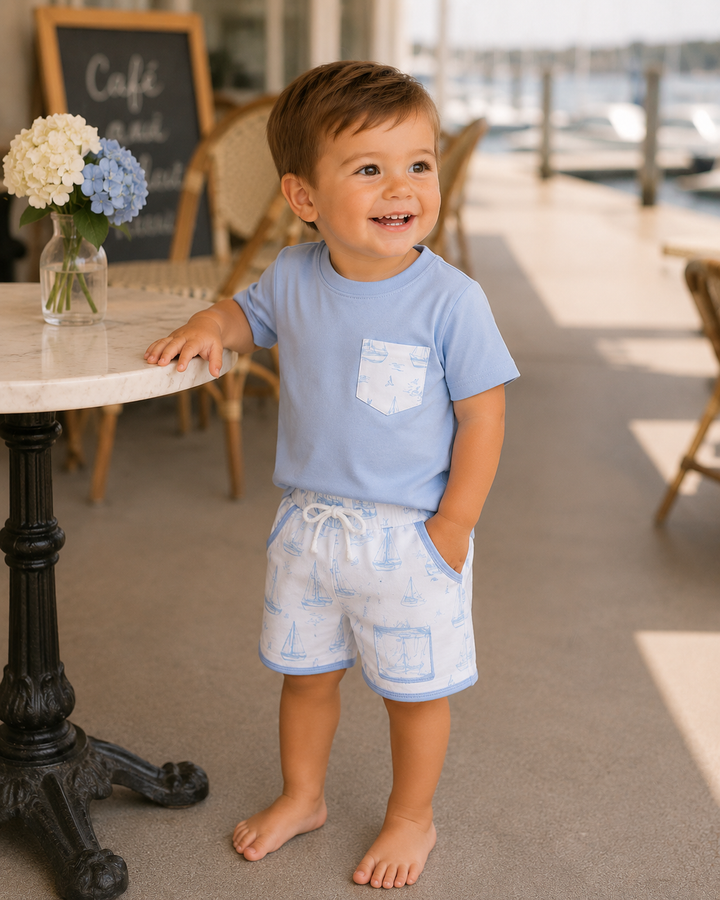 Child in light blue sailboat T-shirt and white printed drawstring shorts set