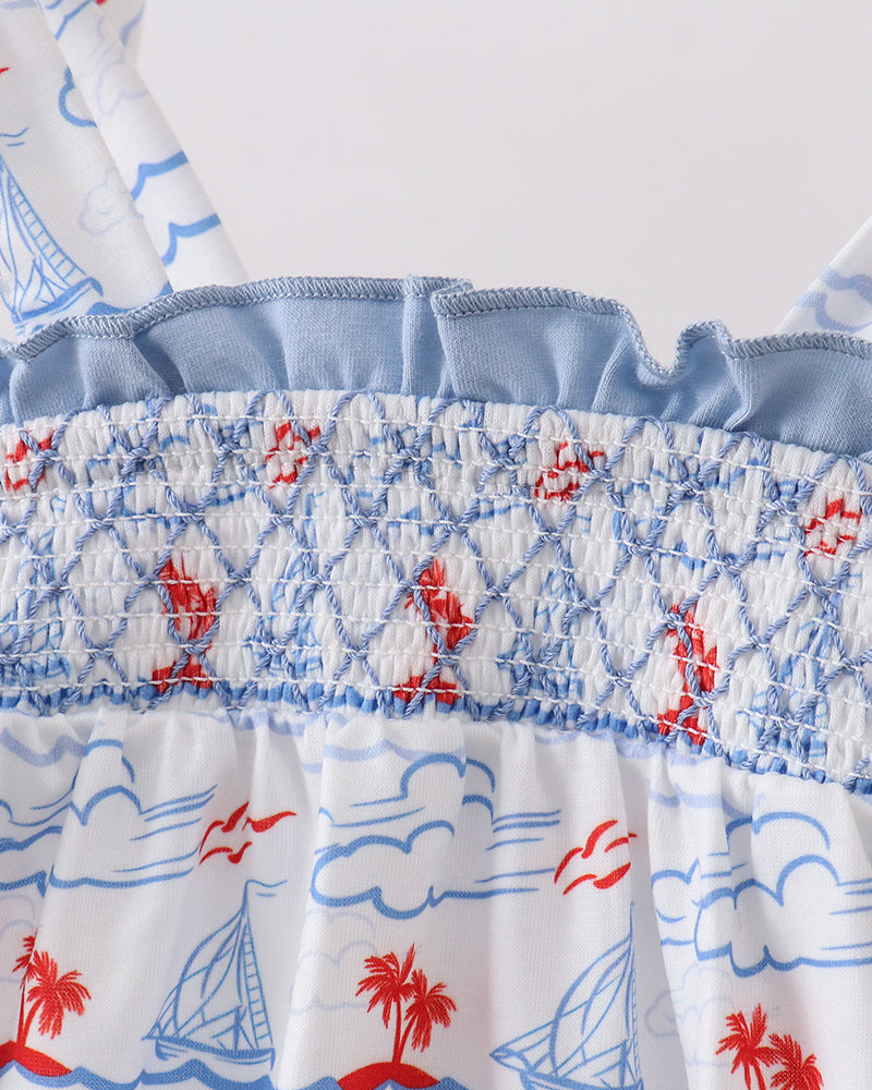 Close-up of a fabric with nautical patterns including palm trees, sailboats, and waves.