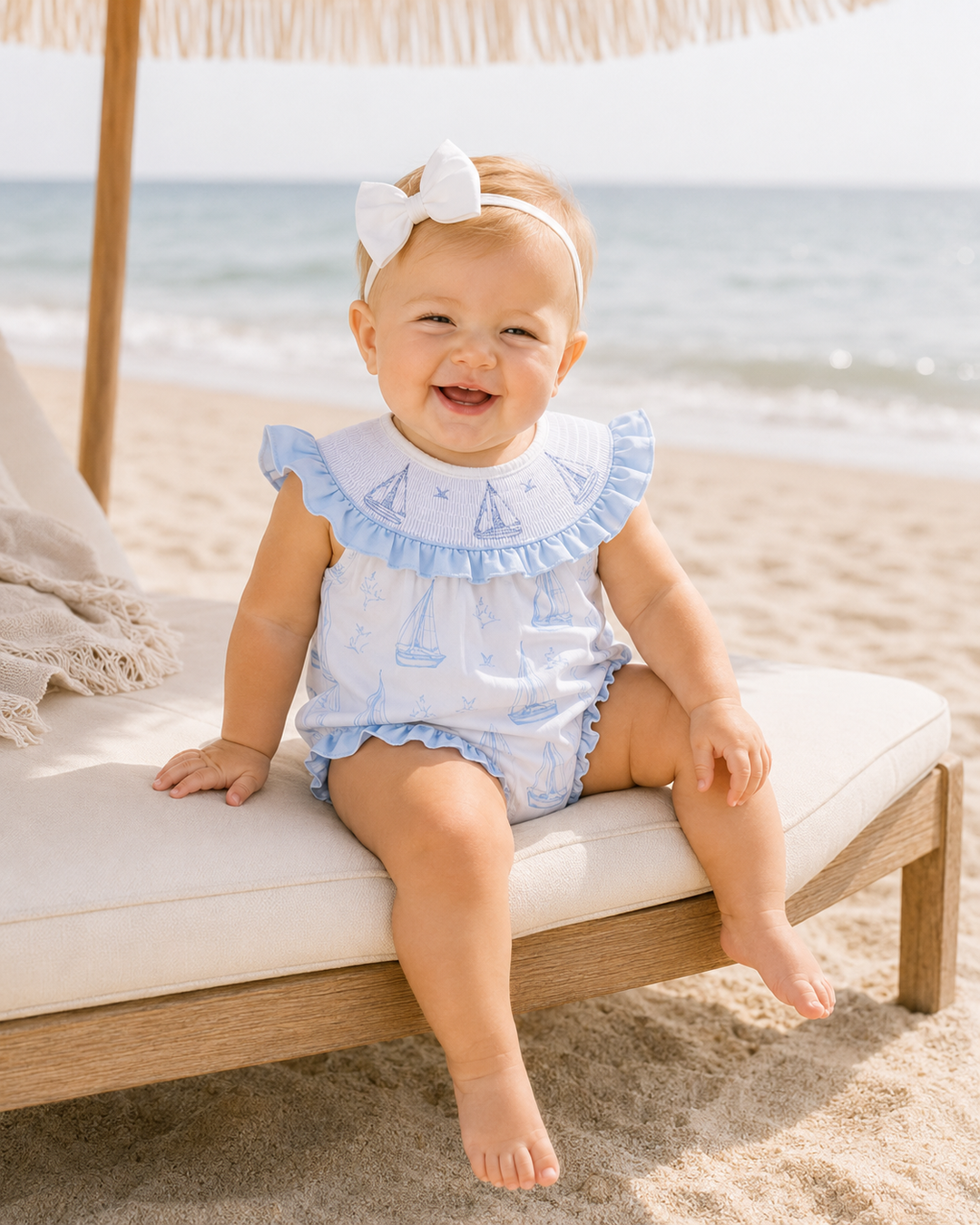 baby girl sitting on a sunbed on the beach