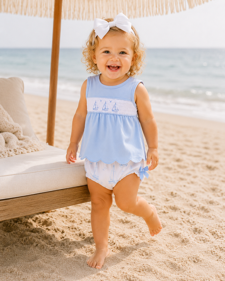 Toddler girl standing under an umbrella on the beach