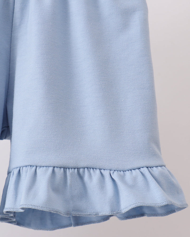 Light blue shorts with ruffled hem on a neutral background