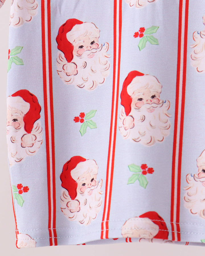 Kids pajama fabric close-up: white with red Santa faces, vertical red stripes, green bows