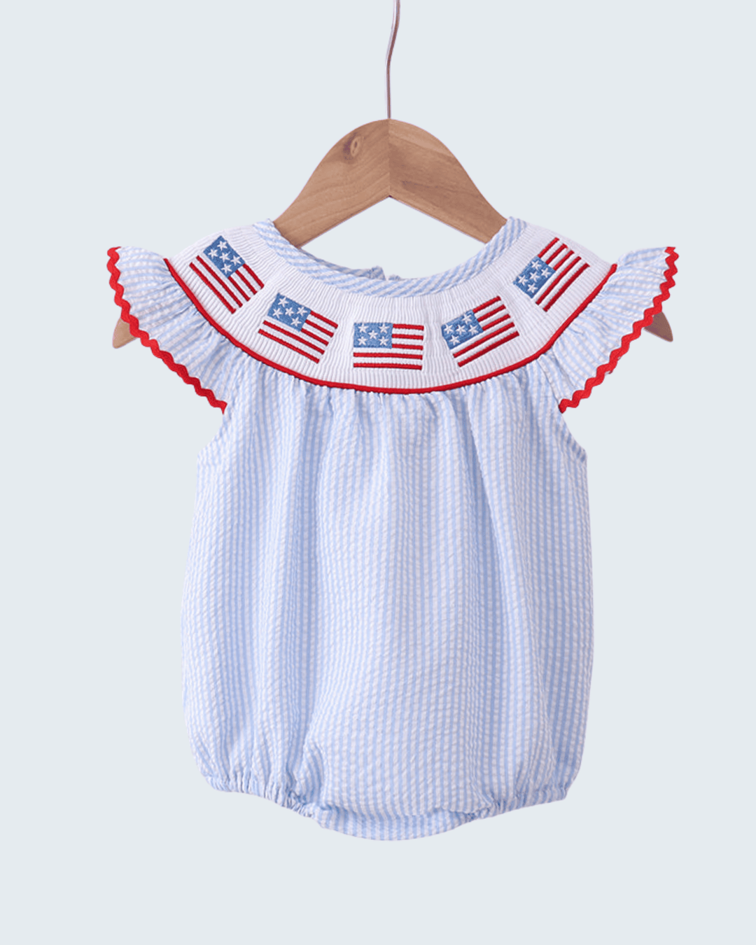 Baby romper with American flag design on a hanger against a white background