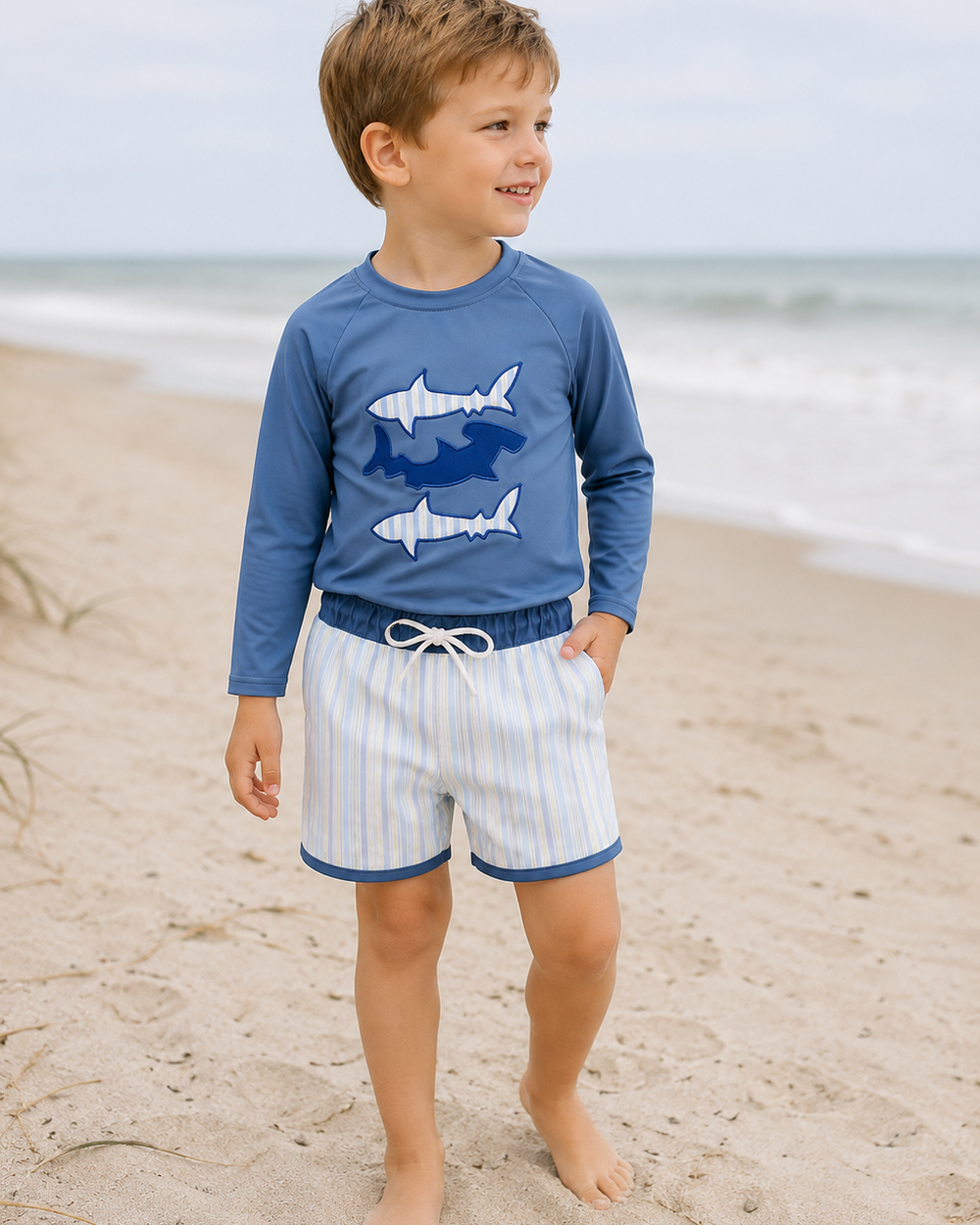 Young boy on beach wearing Blue Shark Applique Stripe 2-Piece Swimsuit
