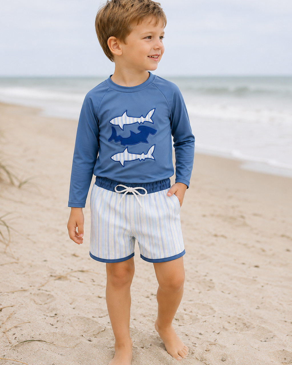 Young boy on beach wearing Blue Shark Applique Stripe 2-Piece Swimsuit