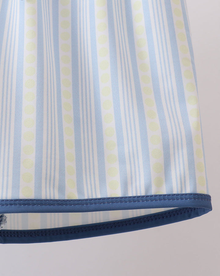 Close-up of a striped fabric with blue, yellow, and white colors on a plain background.
