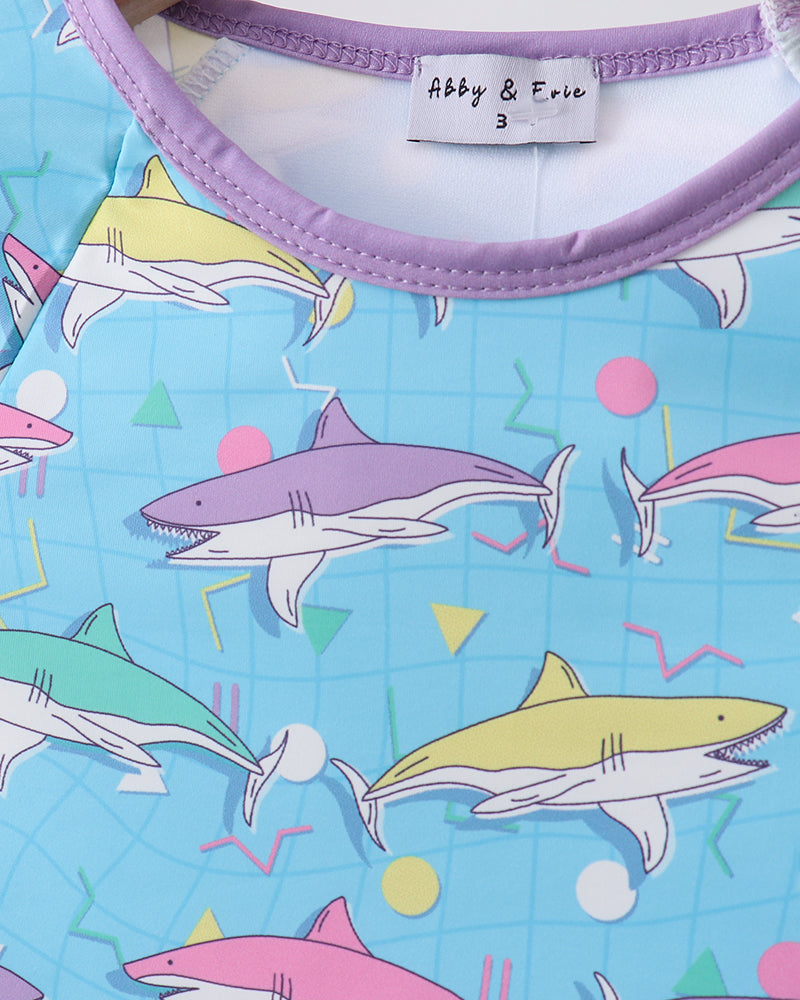 Shirt with colorful shark pattern and brand label on a blue background