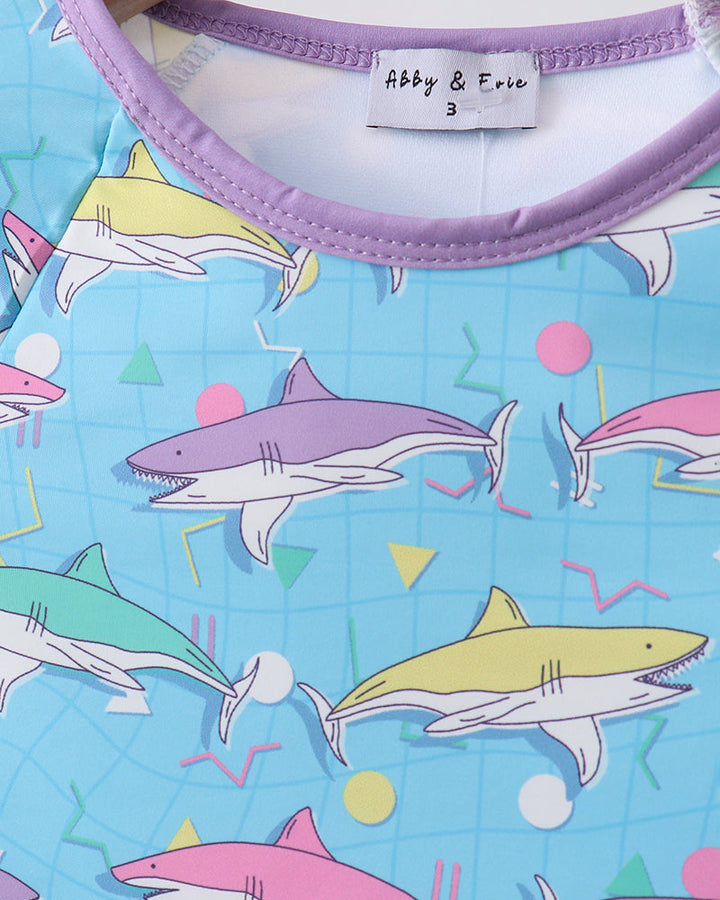 Shirt with colorful shark pattern and brand label on a blue background