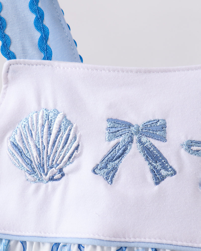 Close-up of a white fabric with blue shell and bow designs.