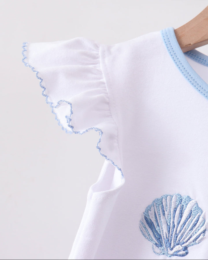 White top with blue trim and shell design on a white background