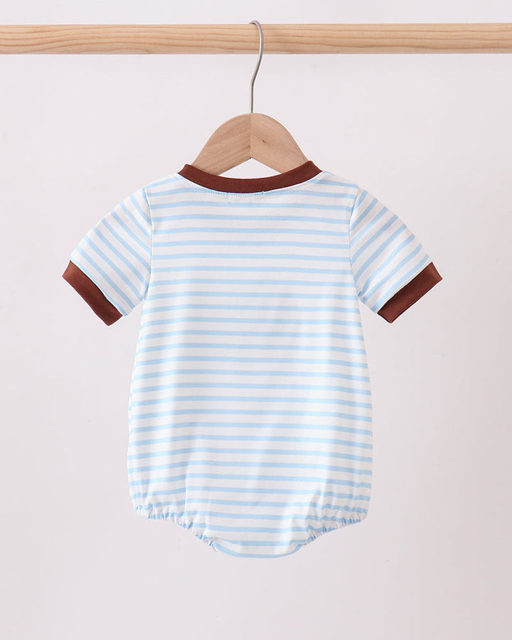 Baby onesie with blue and white stripes and brown accents on a wooden hanger against a beige background