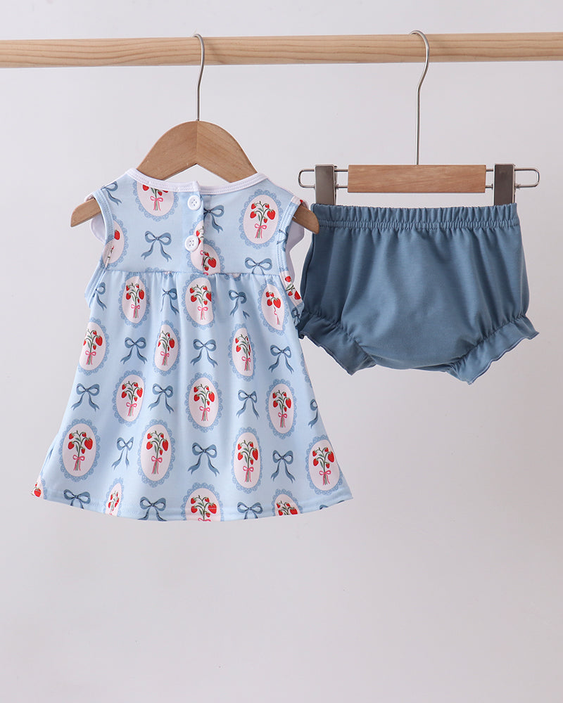 Baby dress with floral and bow pattern and matching bloomers on hangers against a light background
