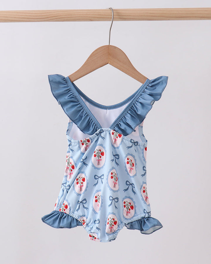 Swimsuit with floral pattern and ruffled collar on a wooden hanger against a white background