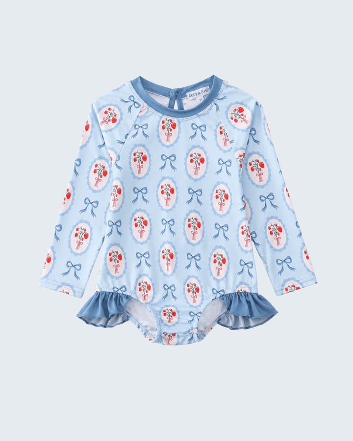 Blue Strawberry Bow Ruffle Rashguard on light blue background
