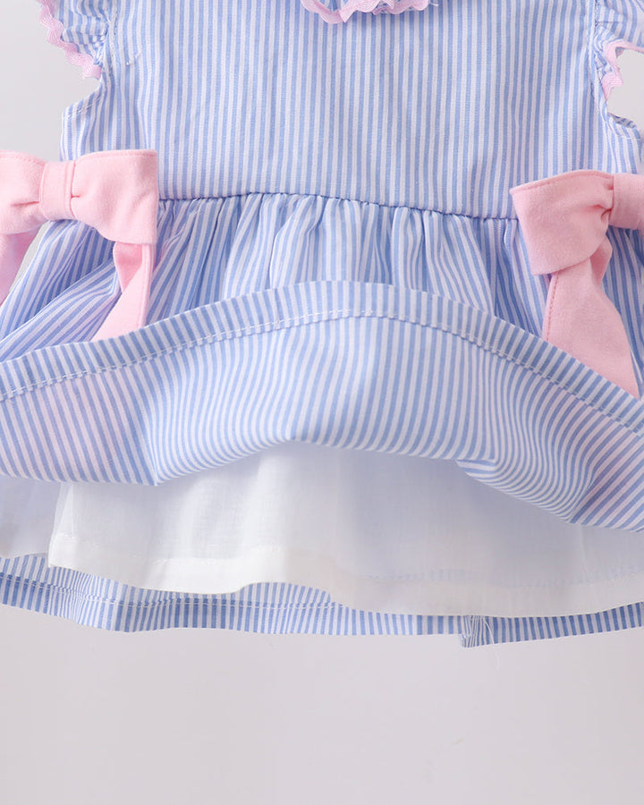 Close-up of a blue and white striped dress with pink bows on a light gray background