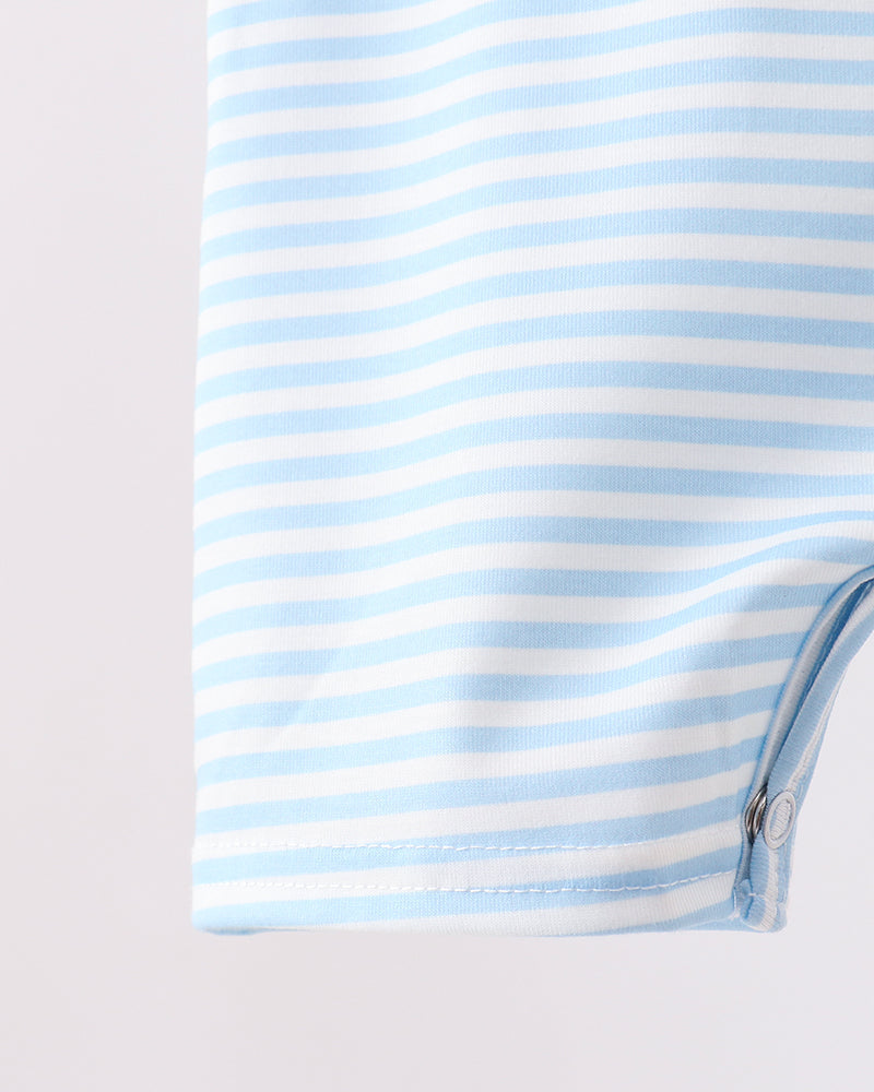 Close-up of a light blue and white striped garment, showing the fabric texture and a snap button closure on the bottom corner.
